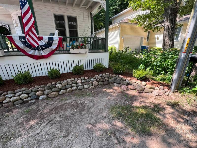 Fieldstone border in front of a porch bed with small shrubs