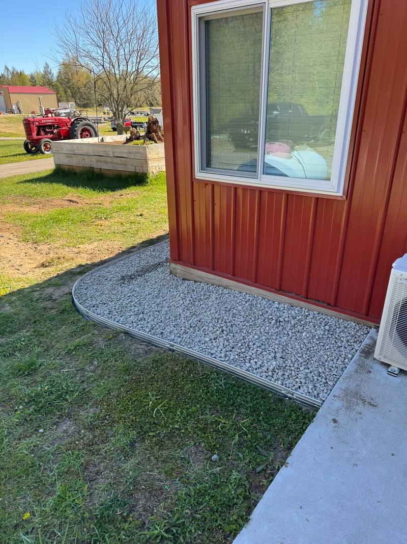 Crushed stone border wrapping a barn corner next to the lawn